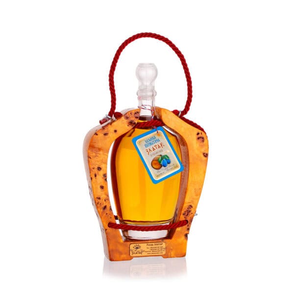 Decorative bottle of traditional fruit rakija in wooden holder, featuring NDV label and vibrant orange color.