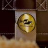 Close-up of a gold lid with mountain symbols and Serbian text, representing traditional Balkan rakija.